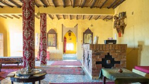 Una habitación tradicional con alfombras estampadas, pared de ladrillo y un banco de madera.