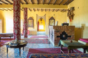 Una habitación tradicional con alfombras estampadas, pared de ladrillo y un banco de madera.