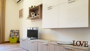 A modern living room with a TV on a cabinet, a bookshelf with decorative items, and a 'LOVE' sign. - crotone house via S Leonardo (Crotone)