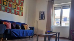 A living room with a blue sofa, a coffee table, and a colorful abstract wall art. - crotone house via S Leonardo (Crotone)