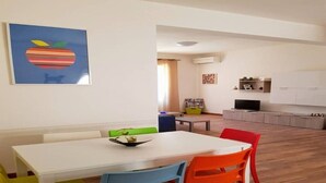 A dining area with a white table and colorful chairs, a kitchen with white cabinets, and a framed picture on the wall. - crotone house via S Leonardo (Crotone)