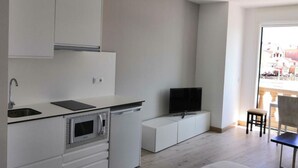 A modern kitchen with white cabinetry, a built-in microwave, and a flat-screen TV. - Studio with sea views (APT 1) (Combarro)