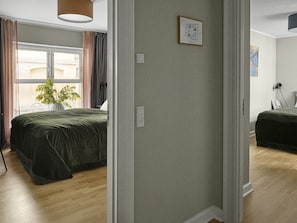 Ein Schlafzimmer mit Bett, einem Fenster mit Vorhängen, einer Pflanze und einer Karte an der Wand.