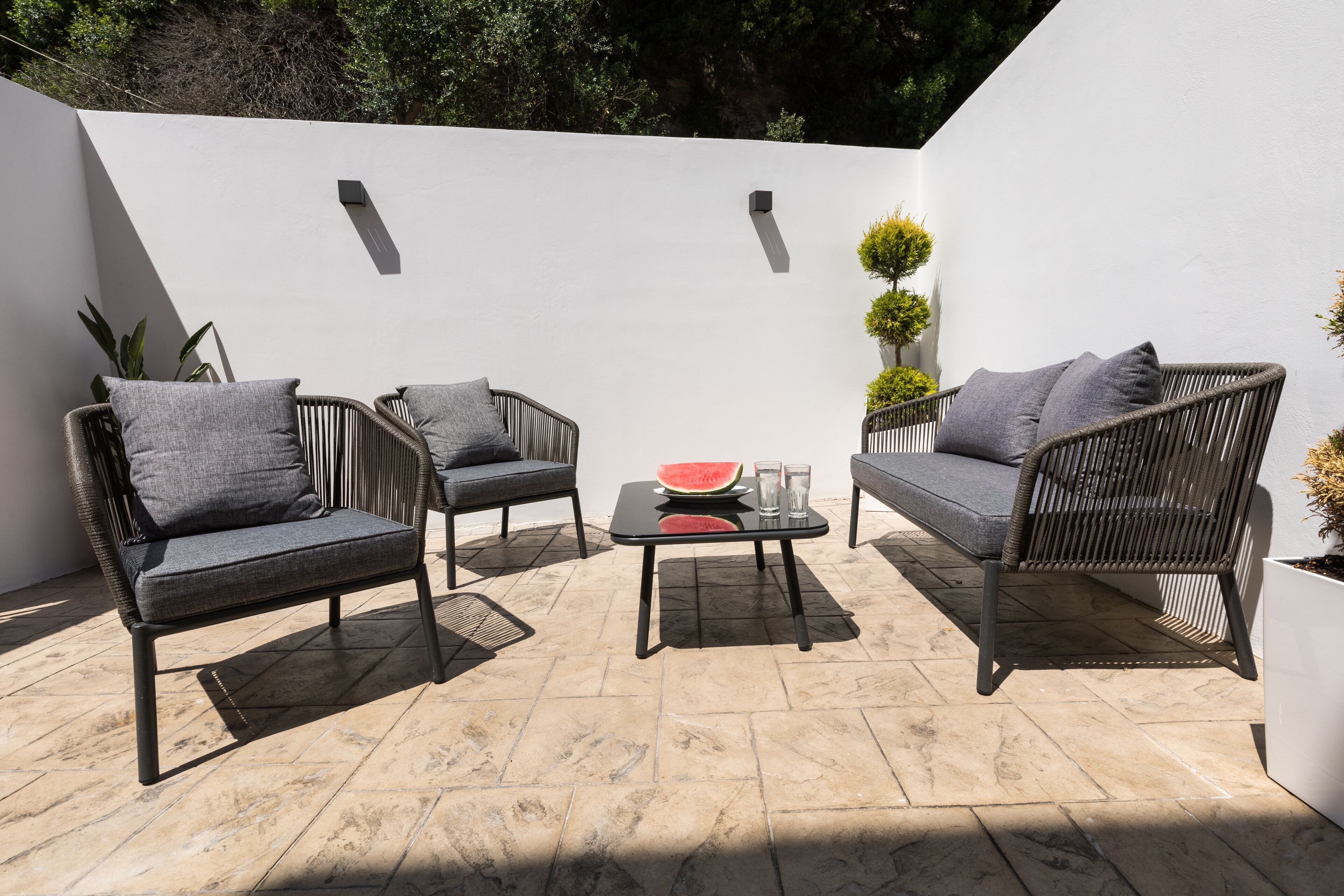 An outdoor patio with wicker furniture, a glass table, and a watermelon.