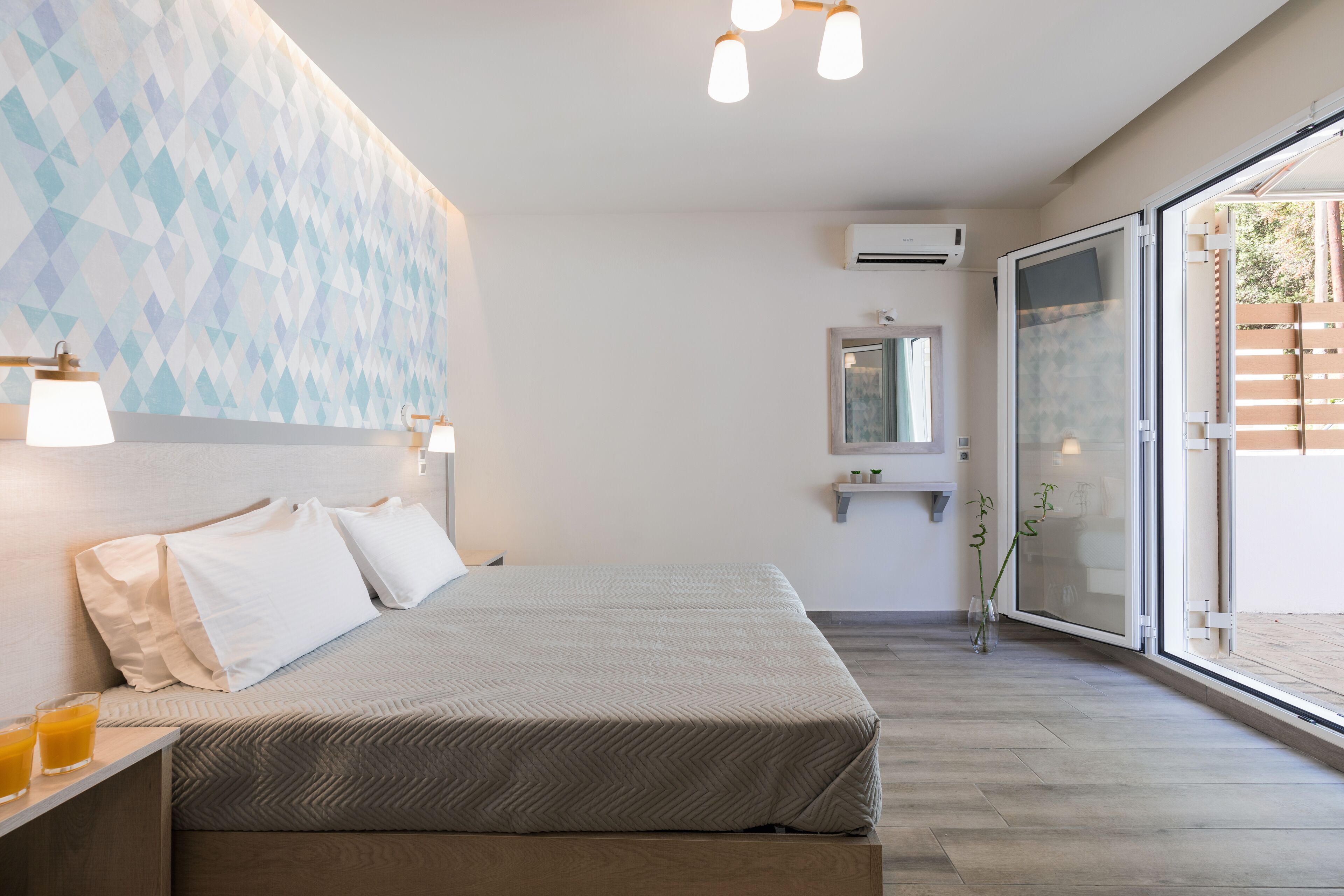 Ein modernes Hotelzimmer mit einem Bett, Nachttischlampen, einem großen Fenster mit Blick und einer Wand-Klimaanlage.