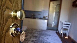 A wooden door with a brass handle and keyhole, leading to a room with a patterned carpet and a visible bathroom in the background. - Boccaccio Room (lastra a signa)