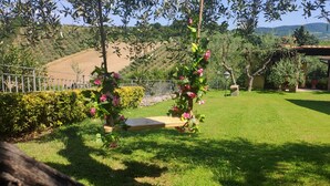 A well-maintained garden with a wooden bench, a pergola with climbing plants, and a view of a hillside. - Boccaccio Room (lastra a signa)