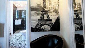 Una habitación con una butaca de cuero negro, un tapete estampado y un mural grande de la Torre Eiffel.