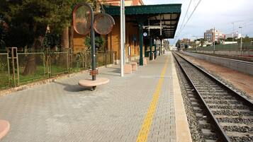 Ein Bahnsteig mit überdachtem Wartebereich, Bänken und einem Zaun.