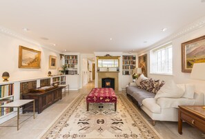 A spacious living room with a fireplace, bookshelves, a sofa, and a patterned rug.