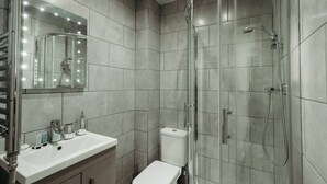A modern bathroom with a glass-enclosed shower, a white sink, and a toilet.