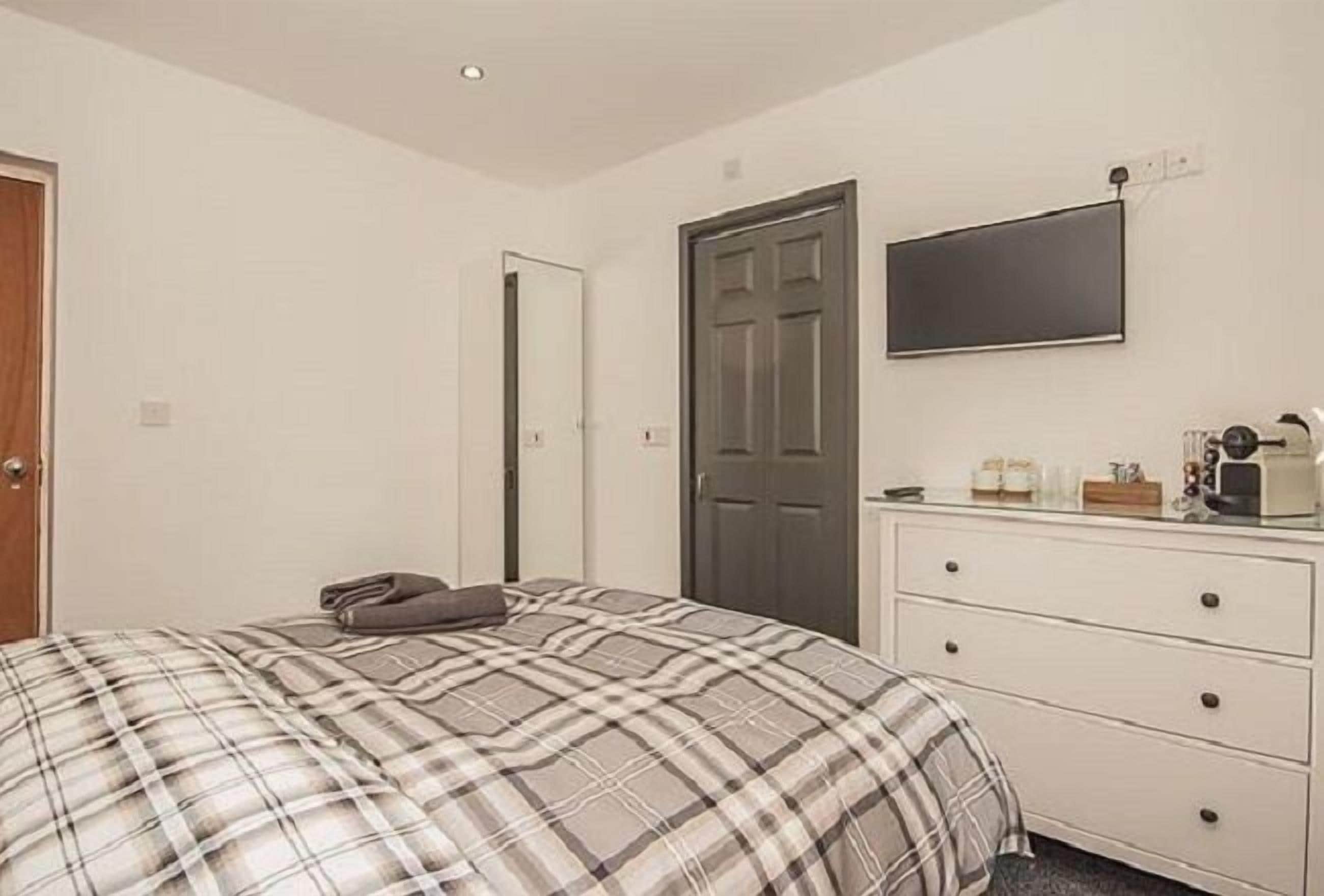 Un dormitorio con una cama, un aparador, un televisor y una puerta.