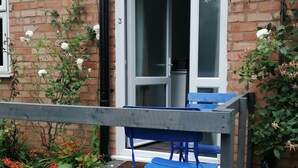 A brick building with a white door and a blue table and chairs outside. - Feather Bed Cottage B&B (Coventry)
