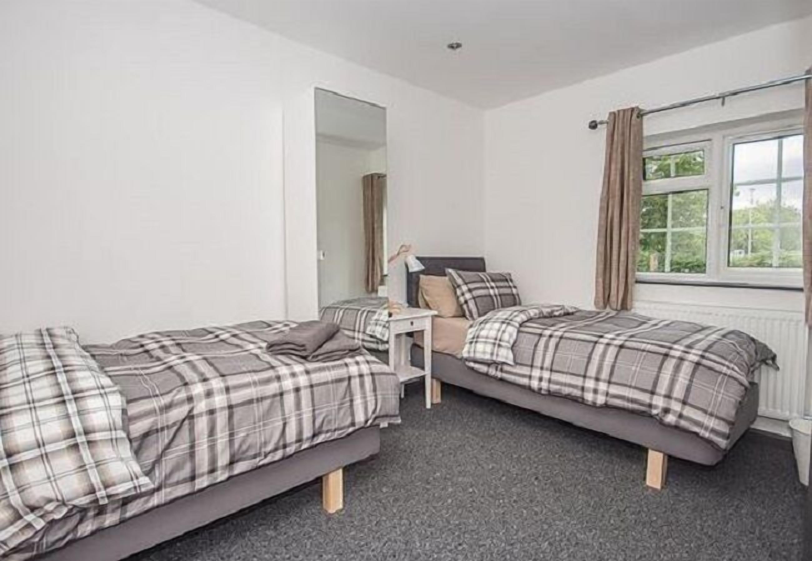 Un dormitorio con dos camas, un escritorio pequeño y una ventana con cortinas.