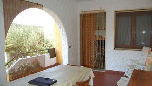 A room with a table and chairs, a window, and an archway leading to an outdoor area.