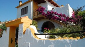 A white building with a balcony and pink flowers.