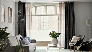 Een moderne woonkamer met een grijze bank, een bijzettafeltje en twee fauteuils.