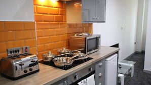 Une cuisine compacte équipée d’un grille-pain, d’un four à micro-ondes, d’une cuisinière et d’un petit réfrigérateur.