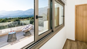 Un balcón con puerta de cristal, puerta de madera y vistas a montañas.