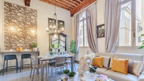 A cozy living room with a dining area, a sofa with patterned cushions, and a chandelier. - ARIAS APARTMENT in the iconic Piazza San Michele (Lucca)