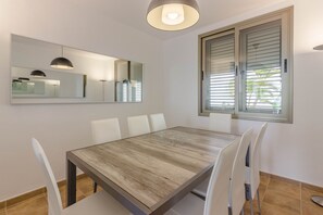 A dining area with a wooden table, white chairs, a large mirror, and a window with blinds. - Villa Isabella, Luxury Villa with Heated Pool Ocean View in Adeje, Tenerife (Adeje, Sc de Tenerife)
