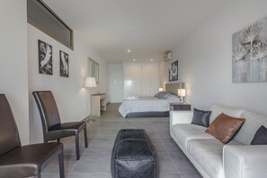 Une chambre d’hôtel moderne équipée d’un lit, d’un canapé, d’une chaise et d’une petite table.