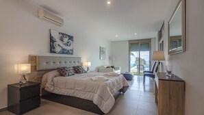 Une chambre moderne avec un grand lit, des tables de chevet, une commode et un miroir.