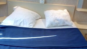 A bed with a blue bedspread and two white pillows. - Capri 39 (Sigean)