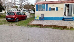 A red car parked in front of a building with a blue and white exterior. - Capri 39 (Sigean)