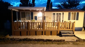 A small, single-story building with a wooden deck and a covered area. - Capri 39 (Sigean)