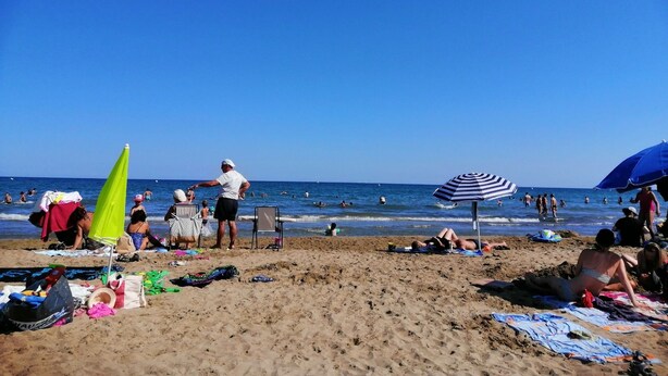 A beach with people sunbathing and swimming, umbrellas, and beach chairs. - Capri 39 (Sigean)