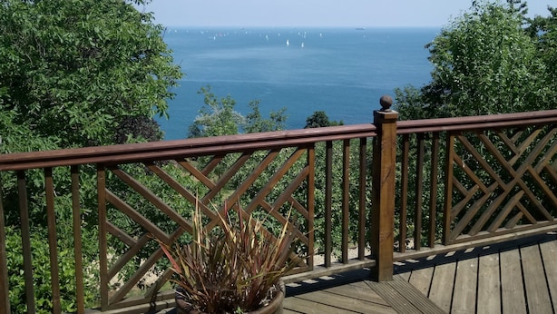 Een houten terras met een spijlenhek dat uitkijkt over een waterpartij met boten.