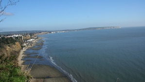 Een kustlandschap met een zandstrand, een heldere blauwe lucht en een verre klif.