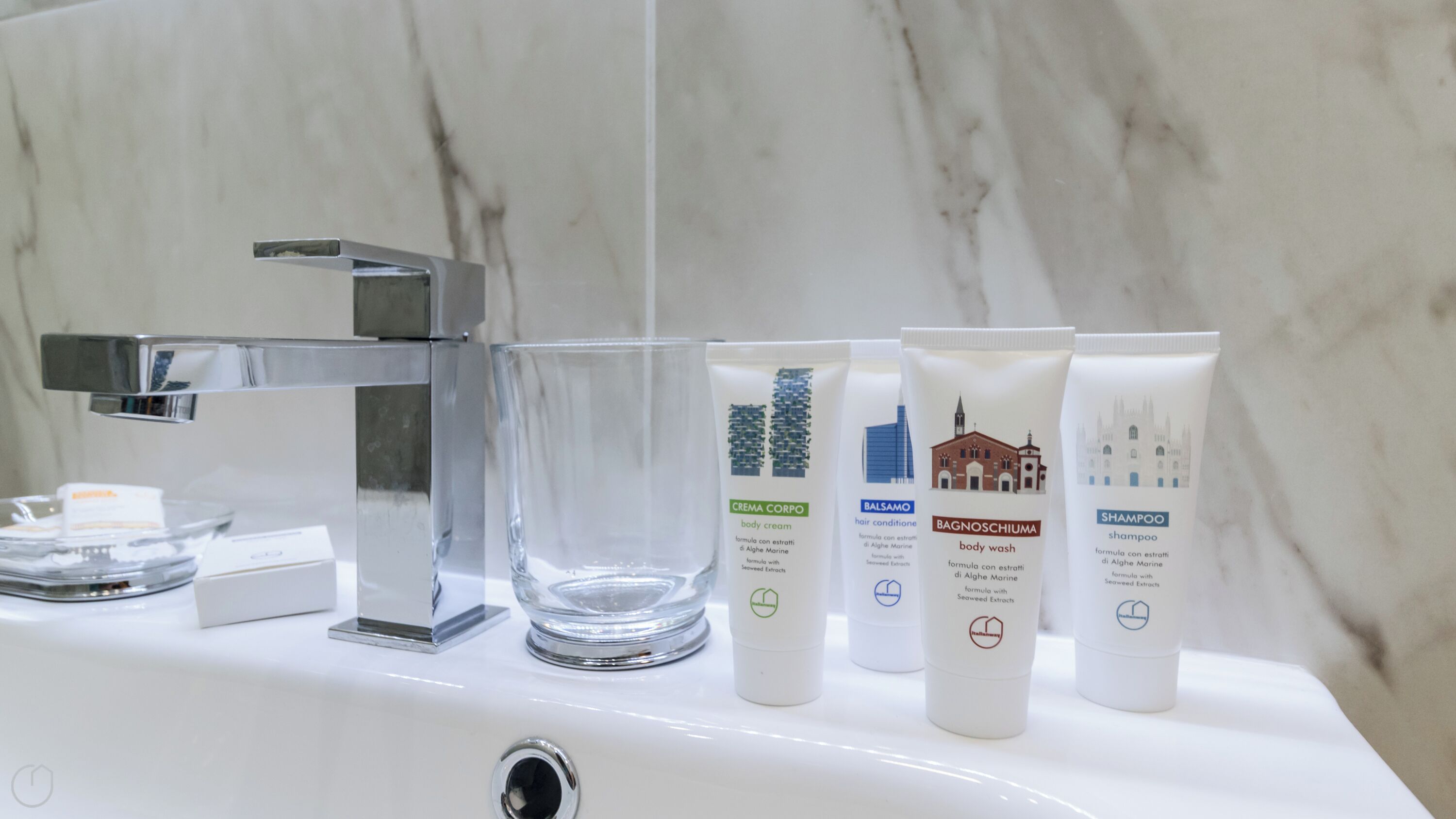 A bathroom sink with four toiletries: body cream, hair conditioner, body wash, and shampoo.
