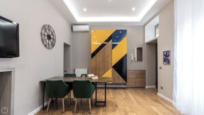 A modern living room with a dining area, a flat-screen TV, a clock, and a unique geometric wall art piece.