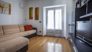 A modern living room with a sofa, a flat-screen TV, and a door leading to another room. - Italianway Easy \- Baiamonti 1 (Milan)