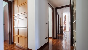 A hallway with wooden flooring and a large wooden door on the left. - Italianway - Lipari 8 (Milan)