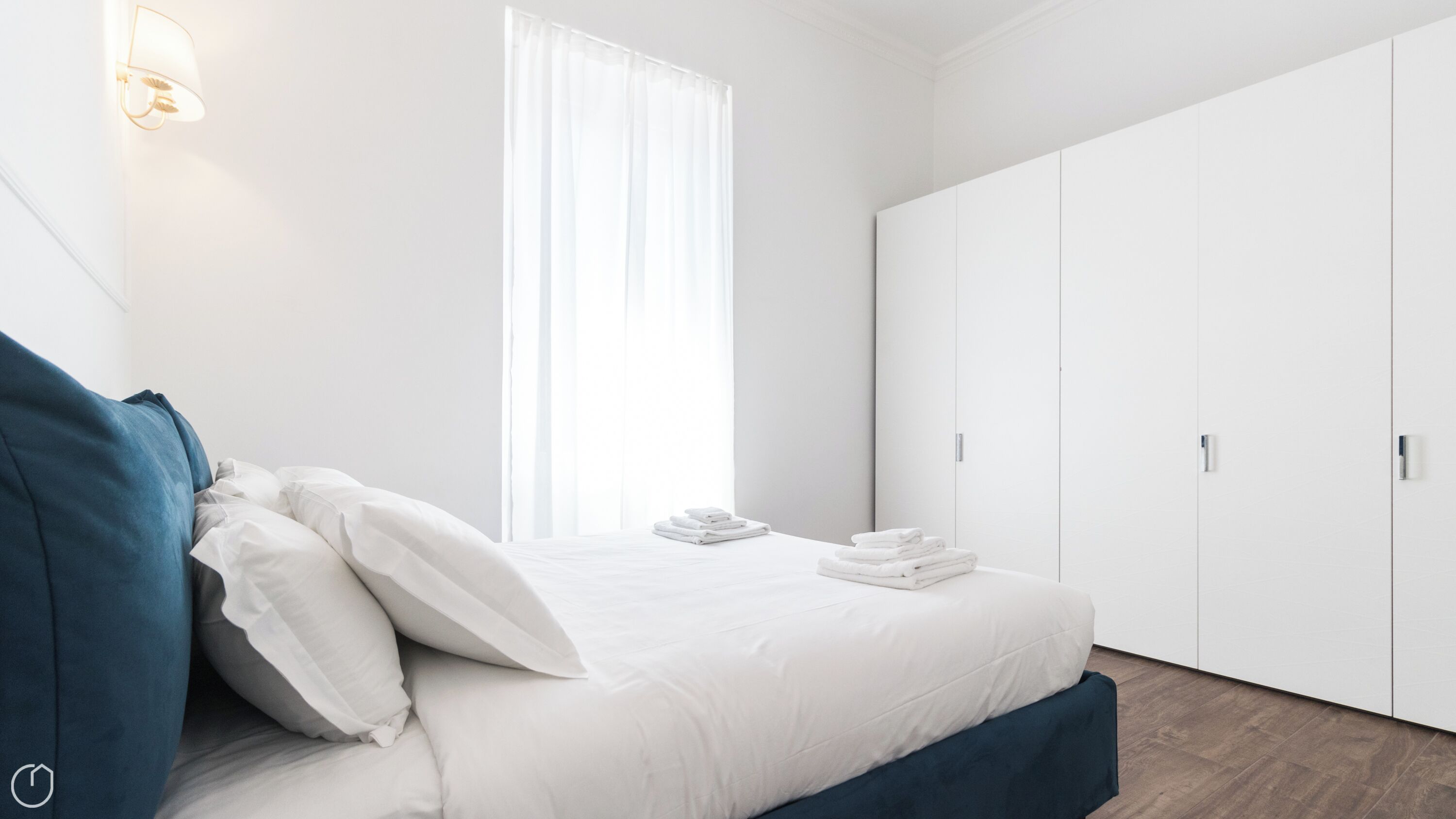 A modern bedroom with a bed, white curtains, a wardrobe, and a nightstand.