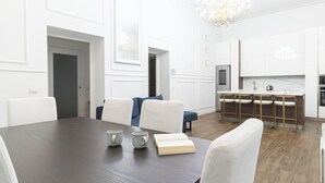Un comedor moderno con una mesa de madera oscura, sillas blancas y una araña.