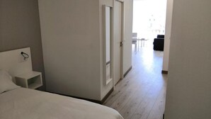 A hotel room with a bed, a bedside table, and a door leading to a hallway. - Superior Sea View Apartment (APT 2) (Poio)