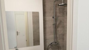 A modern bathroom with a white sink, a mirror, and a shower. - Superior Sea View Apartment (APT 2) (Poio)