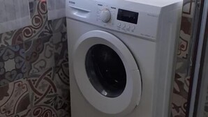 Ein kleiner Hauswirtschaftsraum mit Waschmaschine, gemusterten Fliesen und einer Glastür.