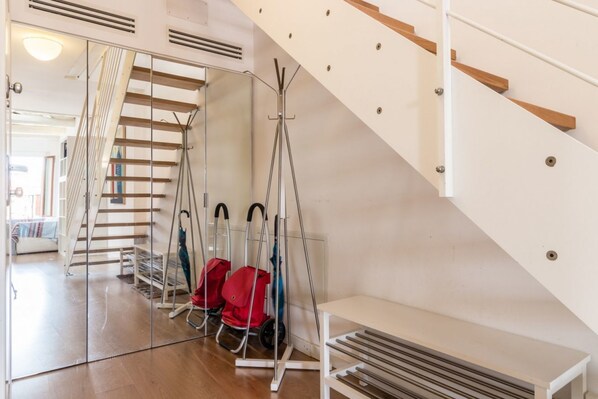 Un interior moderno con una escalera, un perchero y un banco.