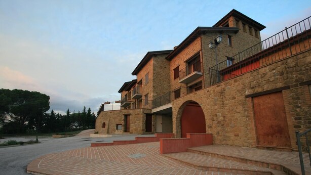 A stone building with multiple balconies and a paved courtyard.