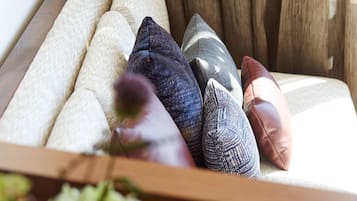 Un sofá con varios cojines en una habitación con paneles de madera y una ventana con cortinas.