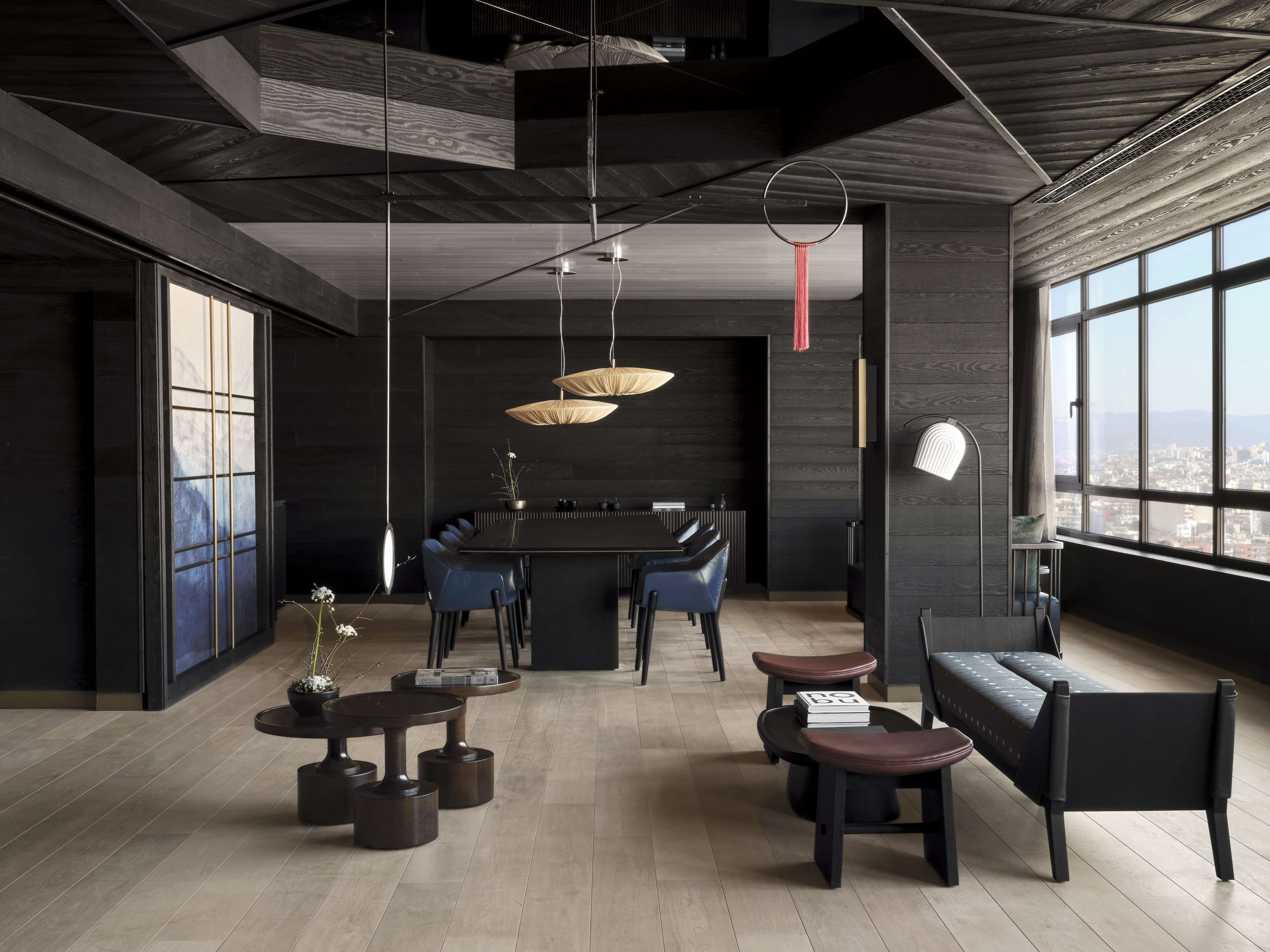 A modern interior with a dining area, seating, and large windows offering a city view.