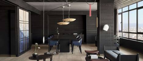 A modern interior with a dining area, seating, and large windows offering a city view.