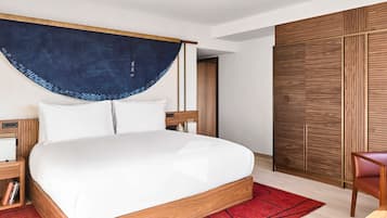 Een moderne slaapkamer met een groot bed, een houten hoofdbord, een nachtkastje met een lamp, een rood vloerkleed en een houten garderobe.