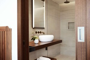 A modern bathroom with a wooden vanity, a white sink, and a mirror.