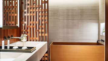 A modern bathroom with a wooden vanity, a freestanding bathtub, and a decorative wooden panel.